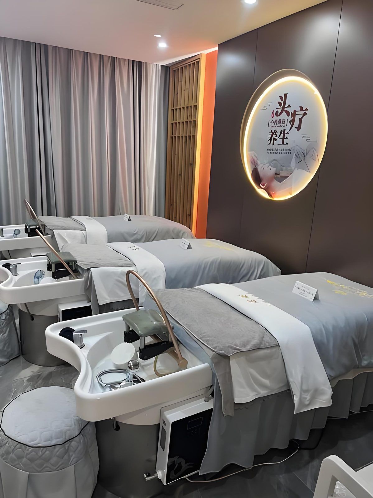 A modern spa room with three beds, each equipped with a sink and a chair.