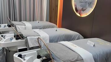 A modern spa room with three beds, each equipped with a sink and a chair.