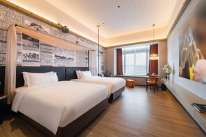 Quarto de hotel com uma cama grande, uma escrivaninha e uma janela com cortinas.