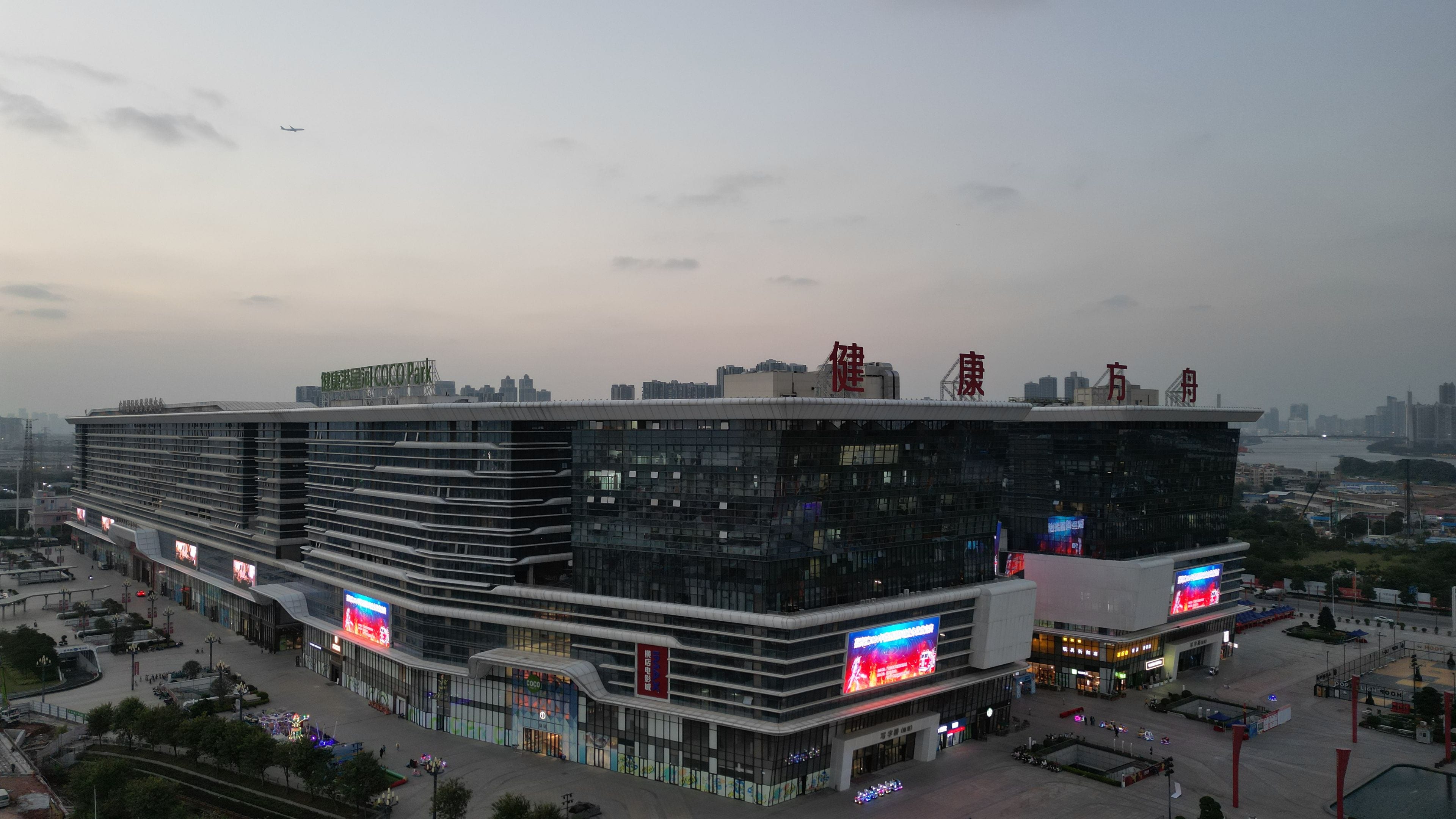 A modern multi-story building with a flat roof, large windows, and a prominent sign on top.