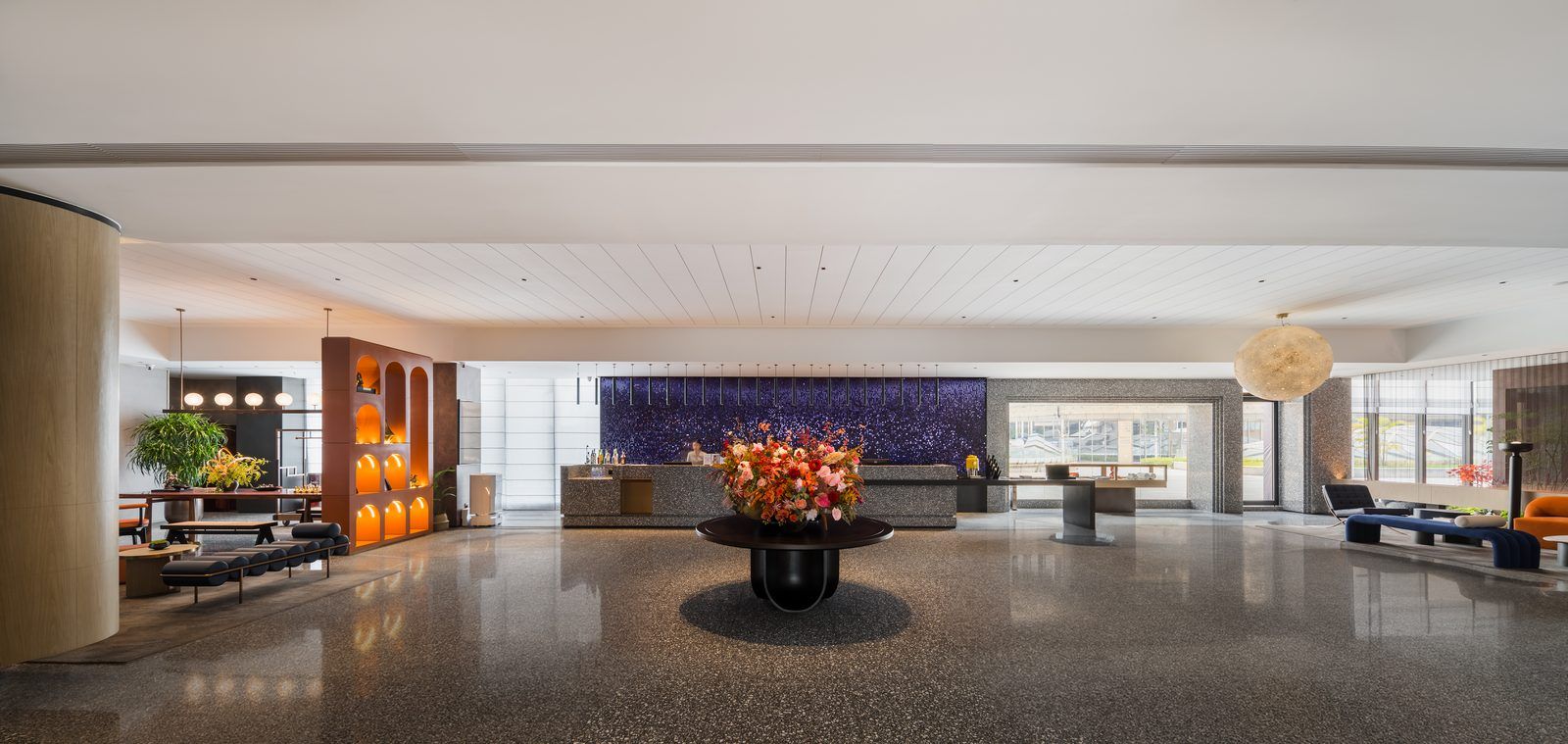A spacious lobby with a reception desk, seating area, and a large decorative wall.