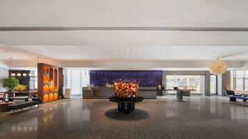 A spacious lobby with a reception desk, seating area, and a large decorative wall.