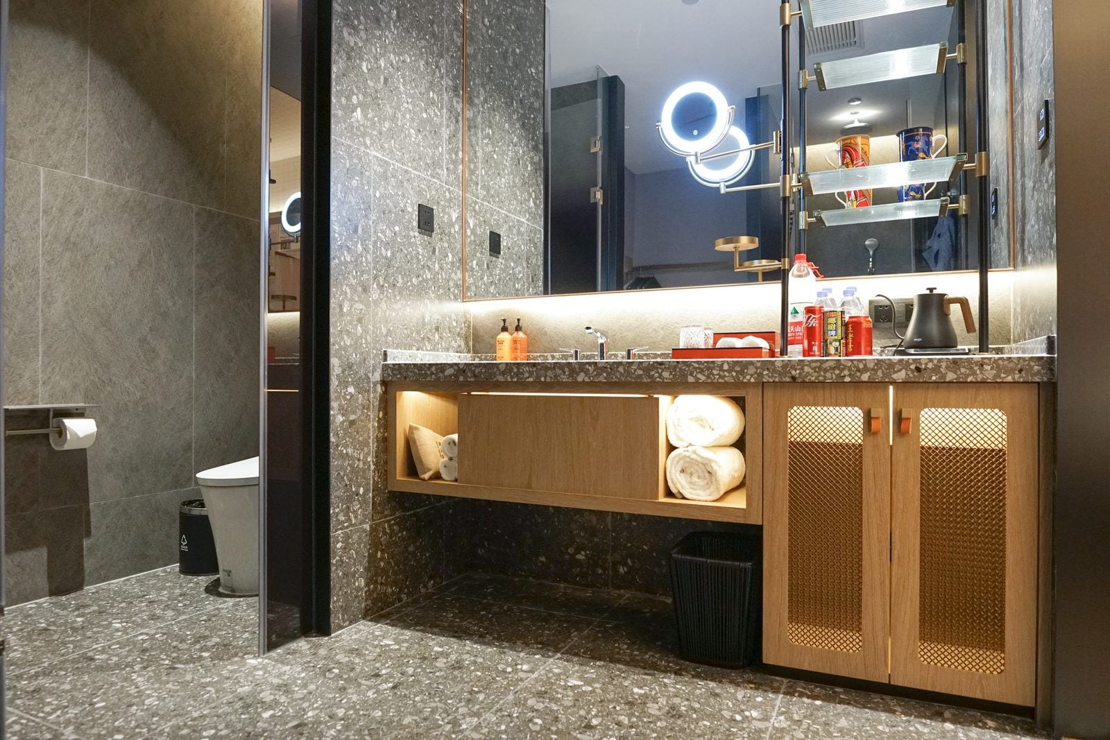A modern bathroom with a granite countertop, a mirror with integrated lighting, and a vanity with storage cabinets.