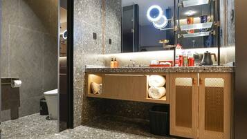 A modern bathroom with a granite countertop, a mirror with integrated lighting, and a vanity with storage cabinets.