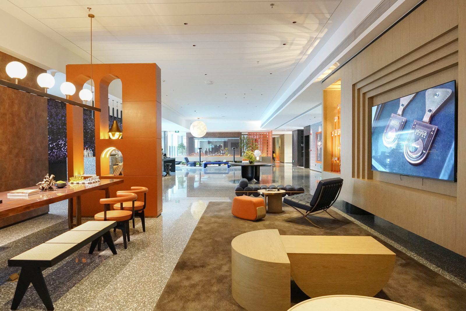 A modern lobby with a reception desk, seating area, and a large screen displaying a product.