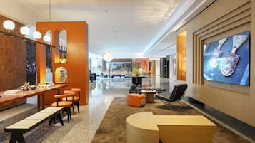 A modern lobby with a reception desk, seating area, and a large screen displaying a product.