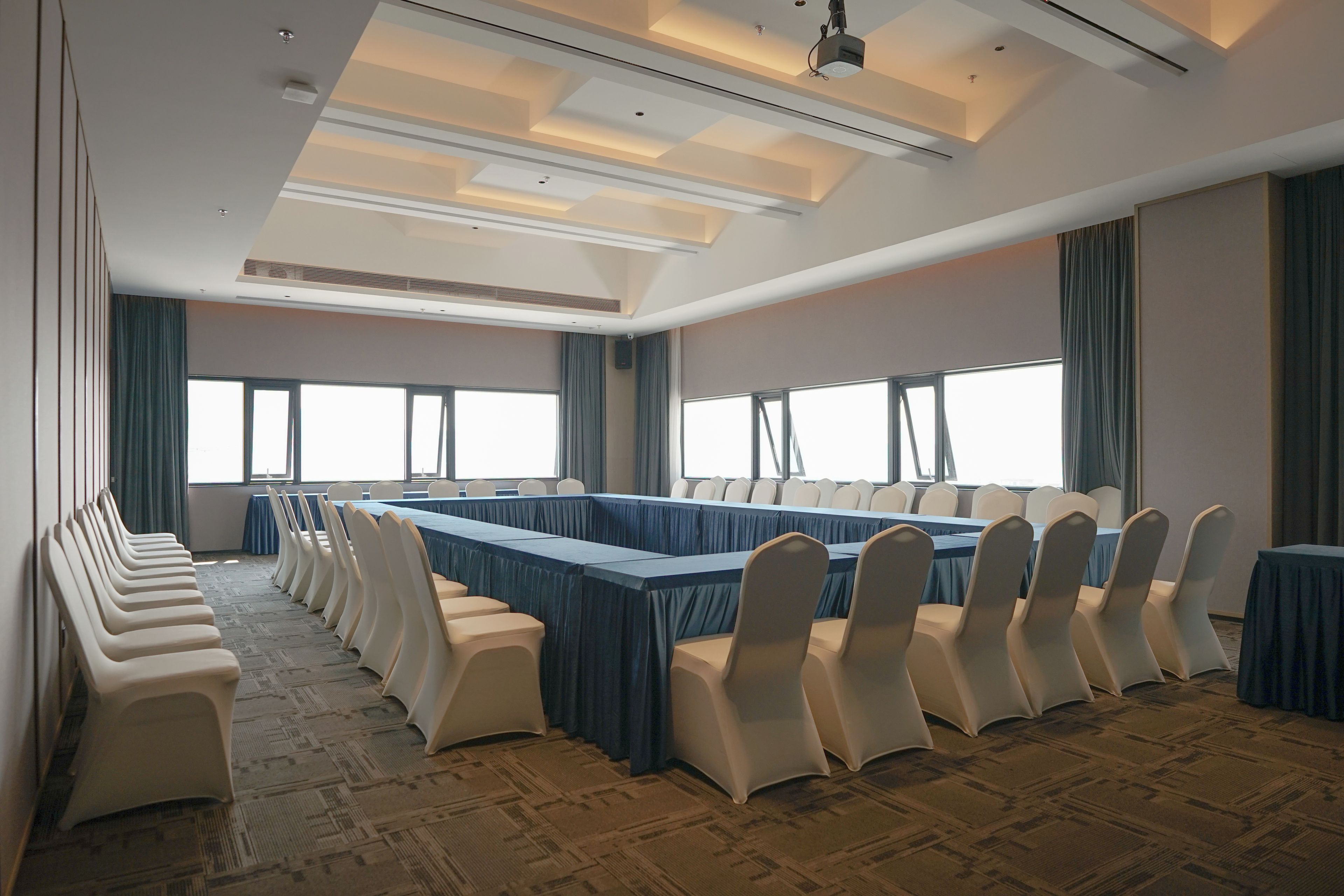 A conference room with a long table, chairs, and large windows.