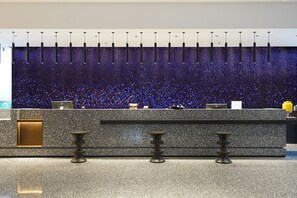 Een modern receptiebalie met een gevlekt granieten aanrechtblad, een flatscreen monitor en een decoratief object op de balie.