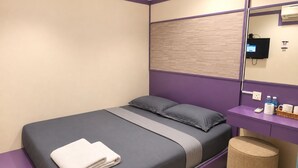 A hotel room with a bed, a vanity with toiletries, and a trash bin.