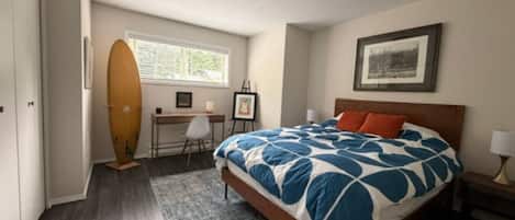 Une chambre avec un lit, un bureau, une planche de surf et une fenêtre.