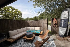 An outdoor patio with a sofa, a small table, and a hammock. - Tofino Surf Retreat — A Cozy Coastal Escape Near Tonquin Beach for 90+ day stays (Tofino)