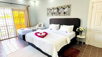 A bedroom with a large bed, a smaller bed, a window with curtains, a zebra artwork on the wall, and a door.