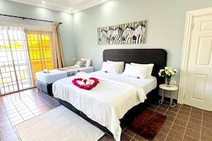 A bedroom with a large bed, a smaller bed, a window with curtains, a zebra artwork on the wall, and a door.
