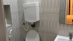 Un baño con inodoro, lavamanos y dispensador de papel higiénico en la pared.