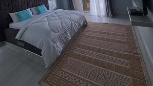 Un dormitorio con cama, ventilador de techo, televisor y ventana con cortinas.