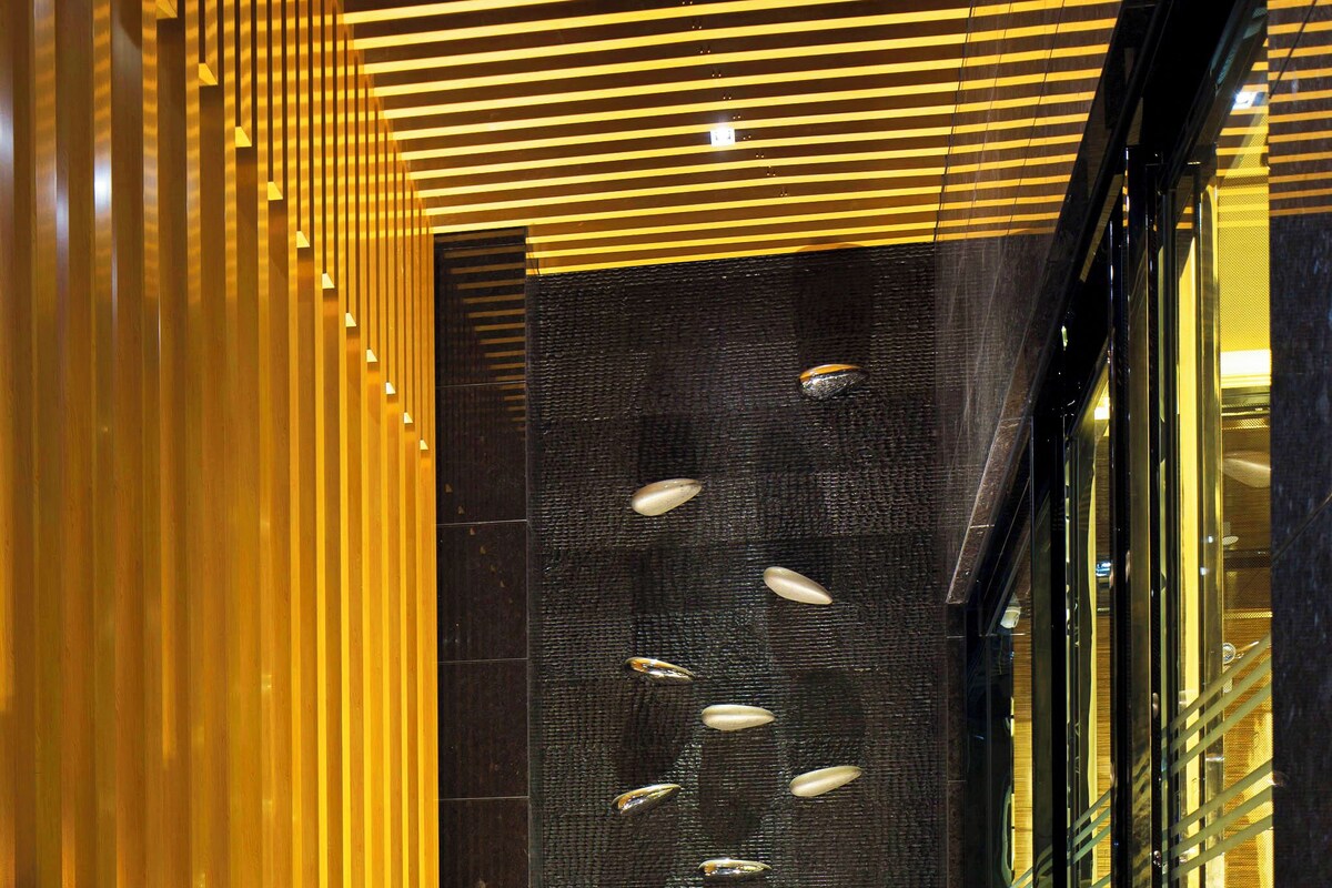 Interior moderno com parede de ripas de madeira, parede texturizada com iluminação embutida e entrada de vidro.