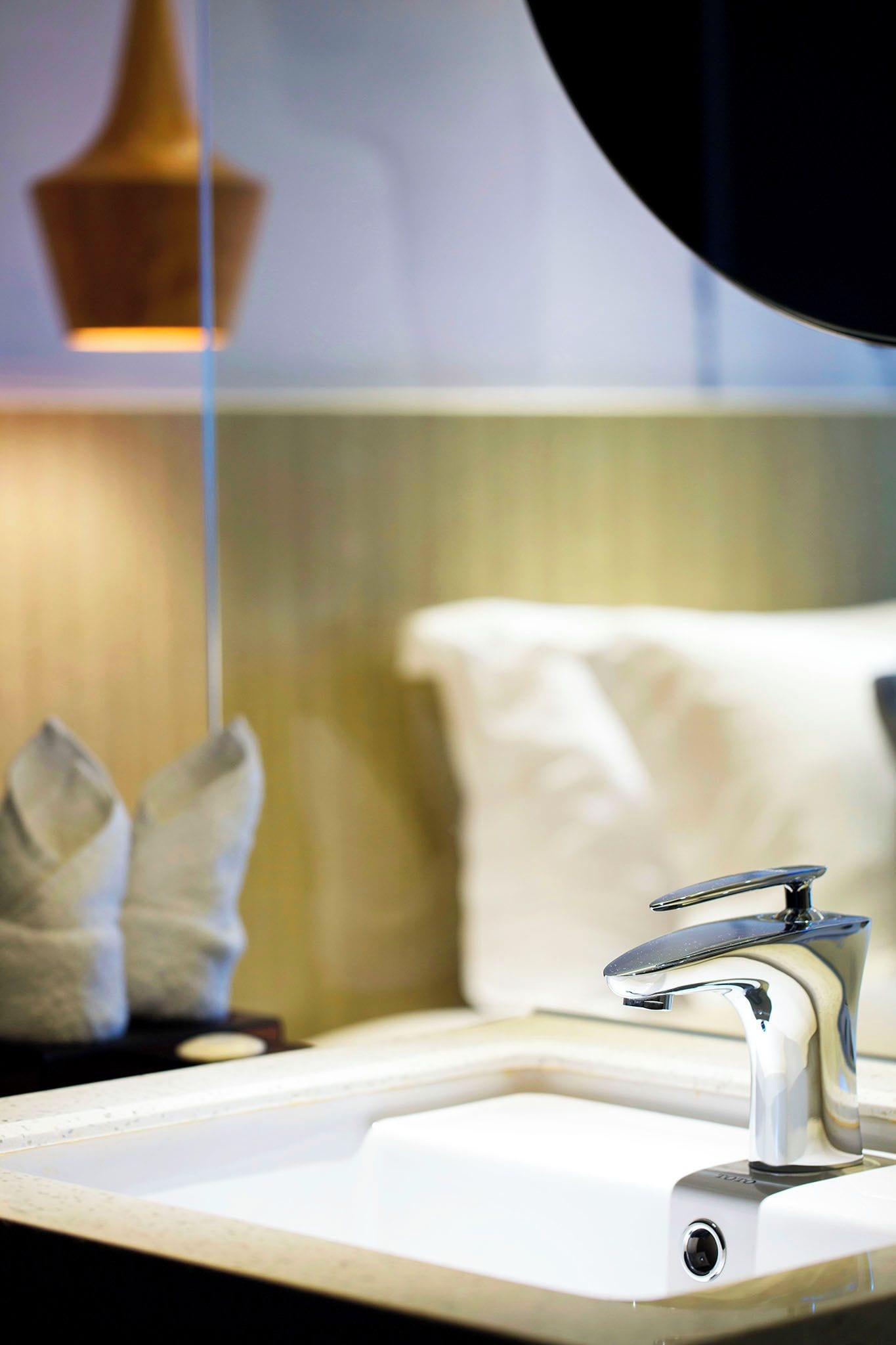 A modern bathroom with a white sink, chrome faucet, and a towel rack.