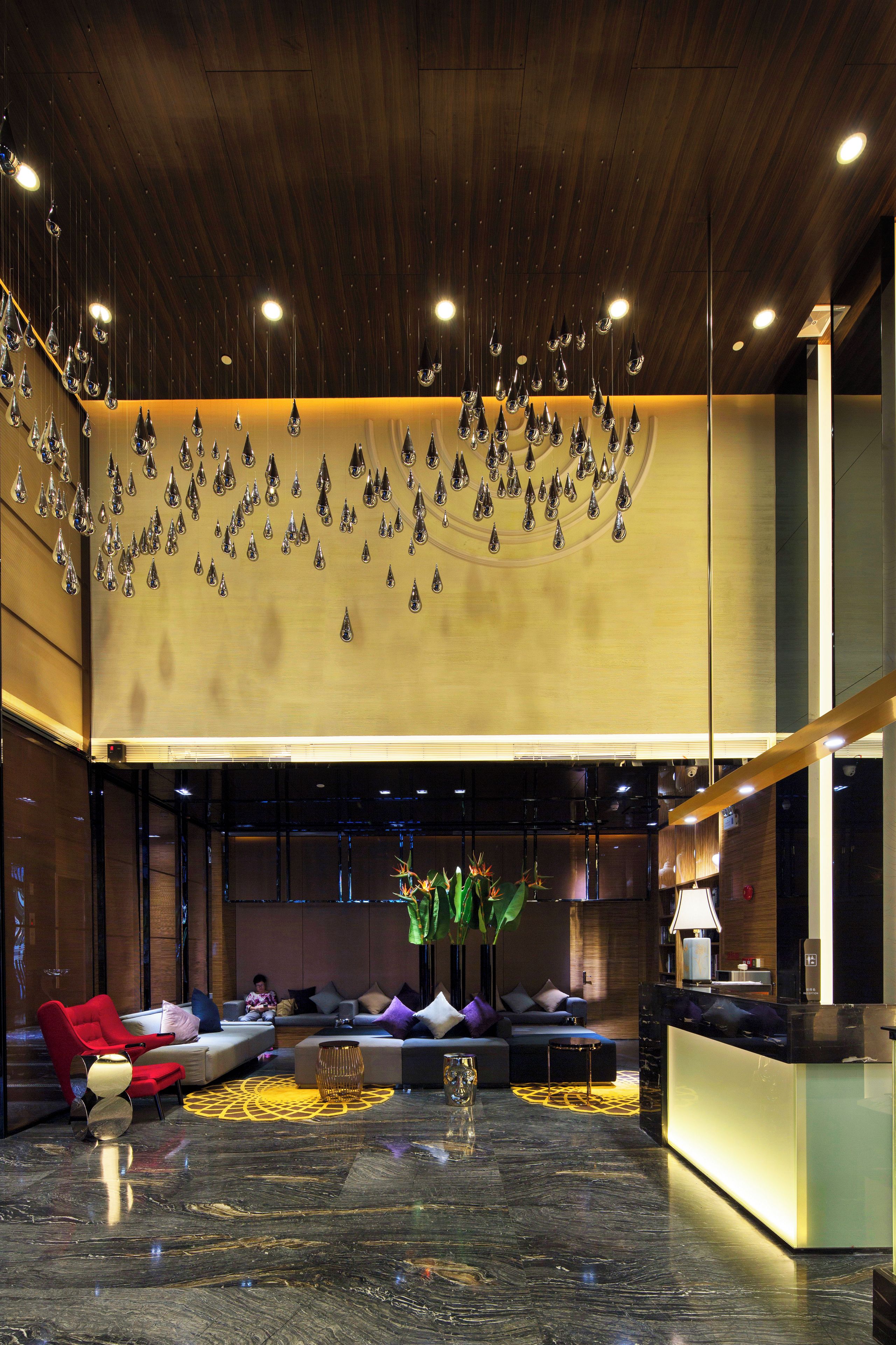 A modern lobby with a wooden ceiling, a reception desk, and seating areas.