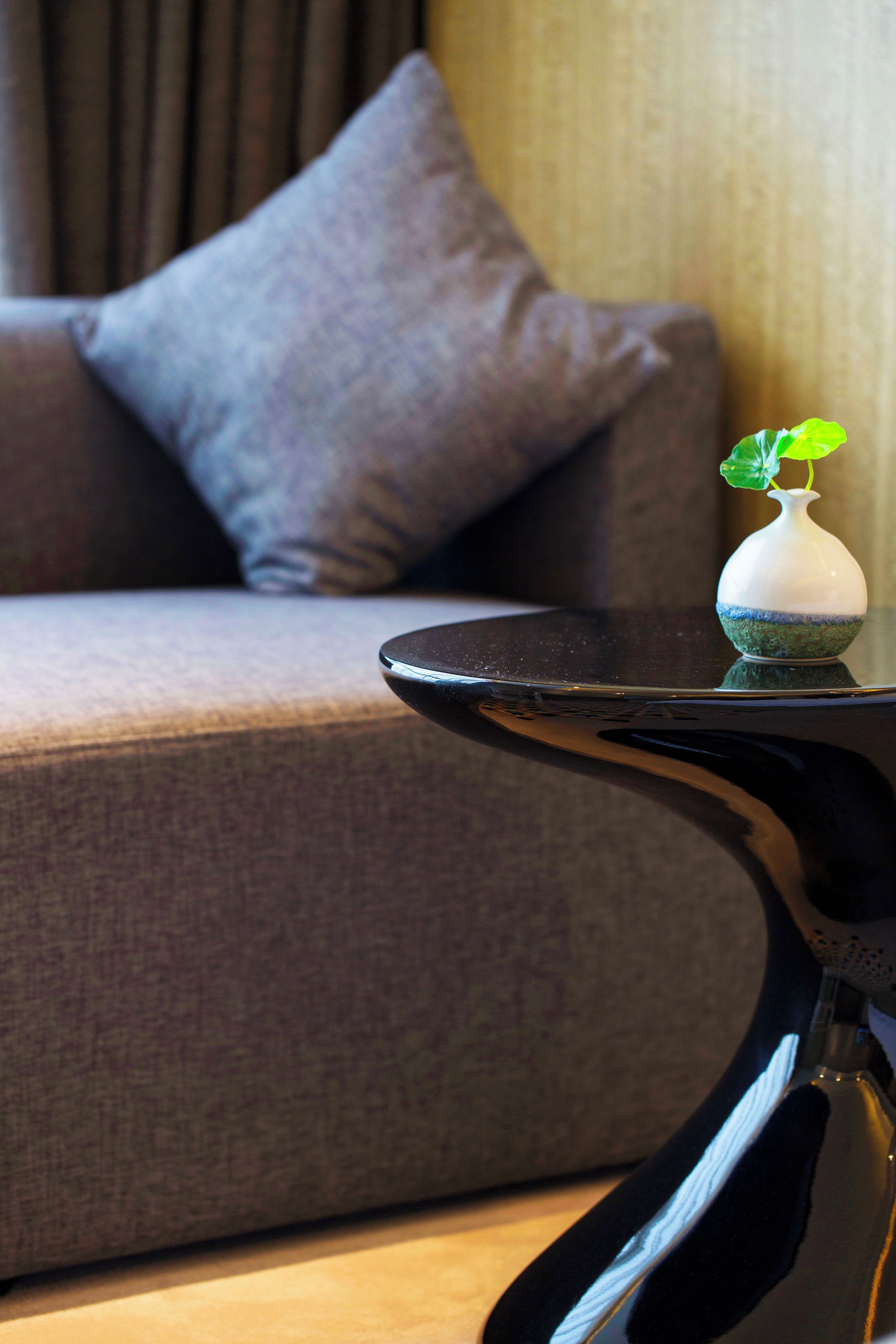 A modern interior with a sofa, a small table, and a vase with a plant.