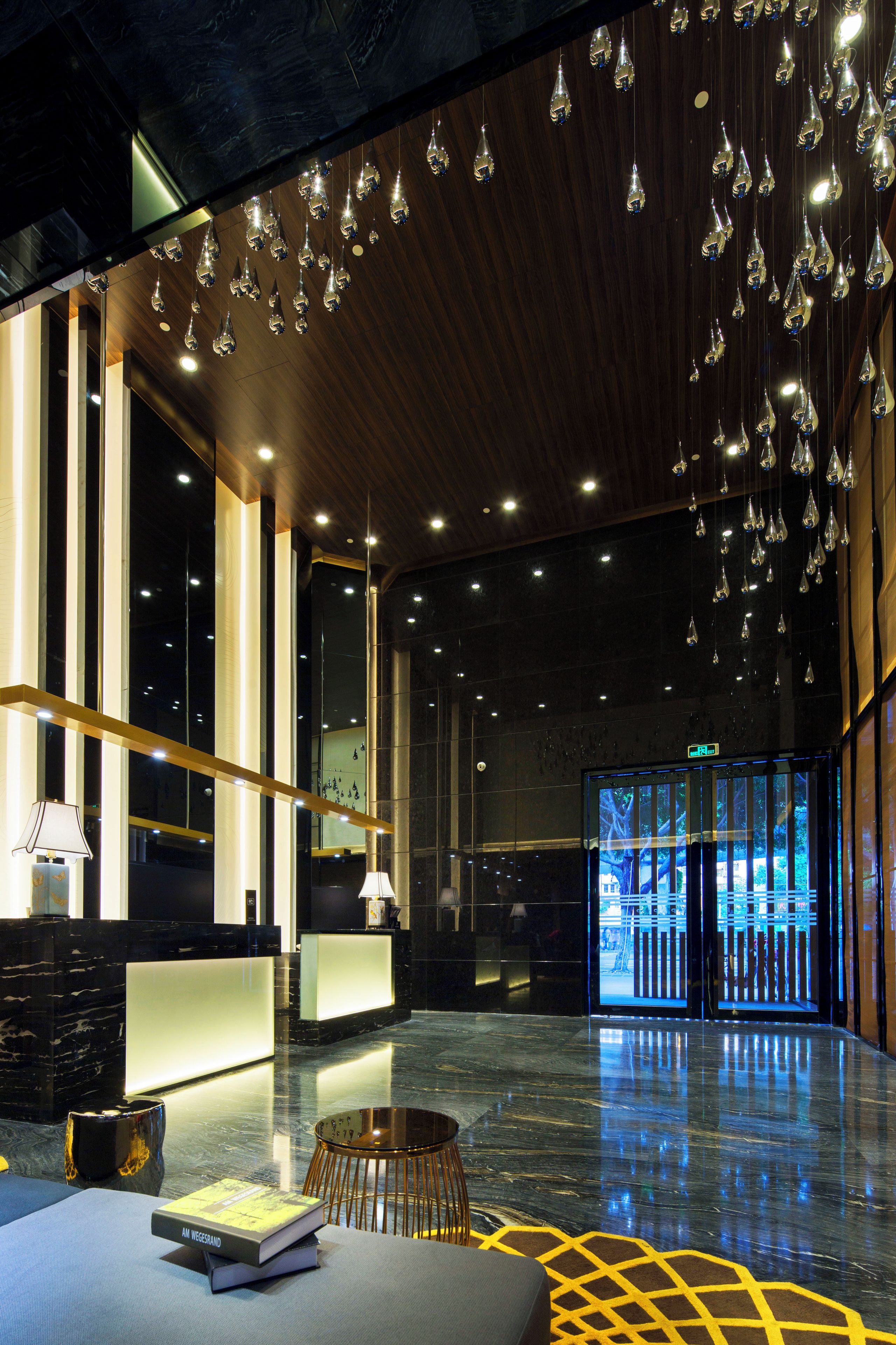 Um lobby moderno com balcão de recepção, área de estar e um grande painel digital.