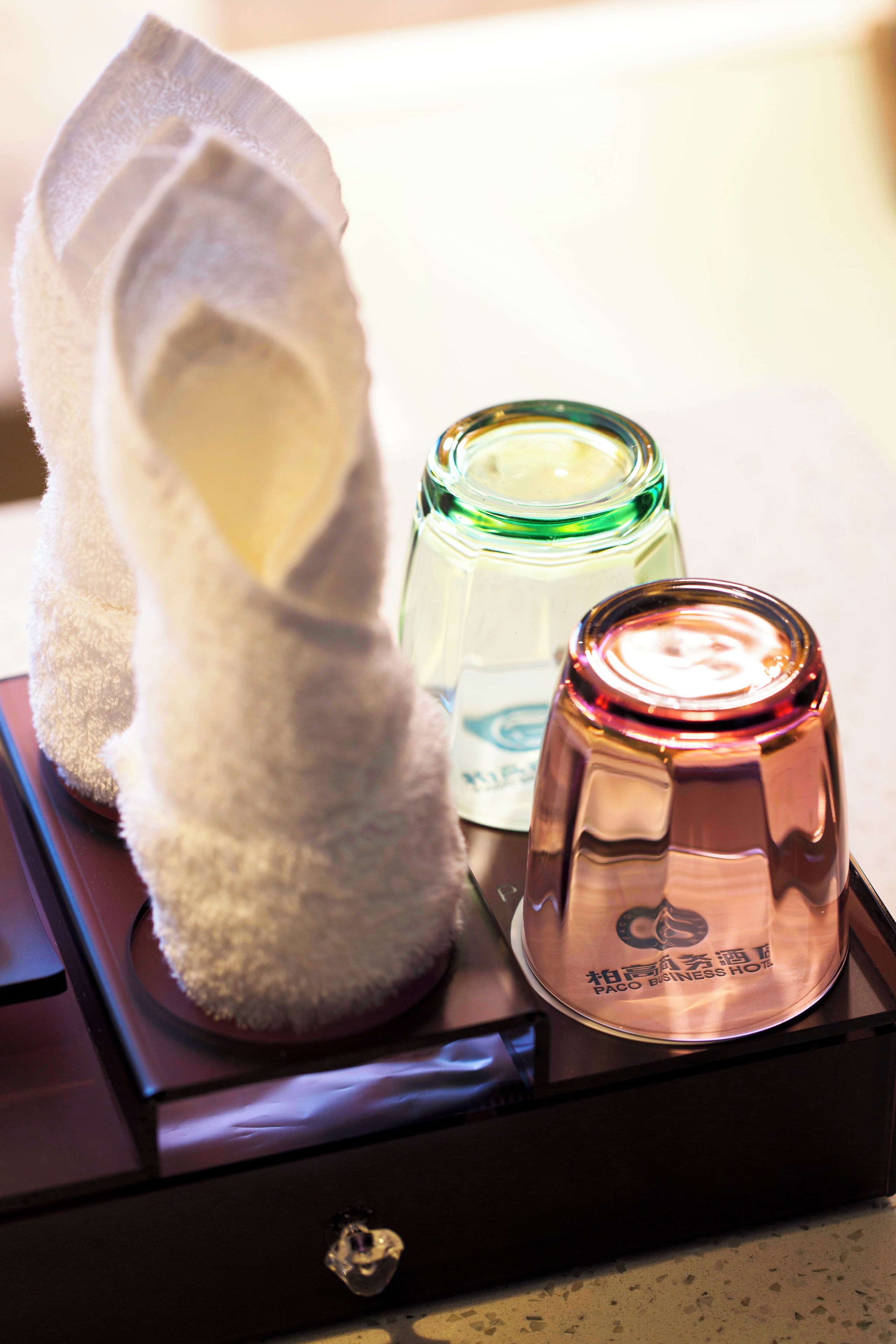 A towel, a green glass bottle, and a copper-colored bottle on a tray.