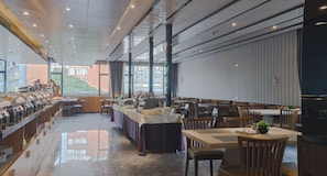 Um restaurante espaçoso com pé-alto, janelas amplas e diferentes opções de assentos.