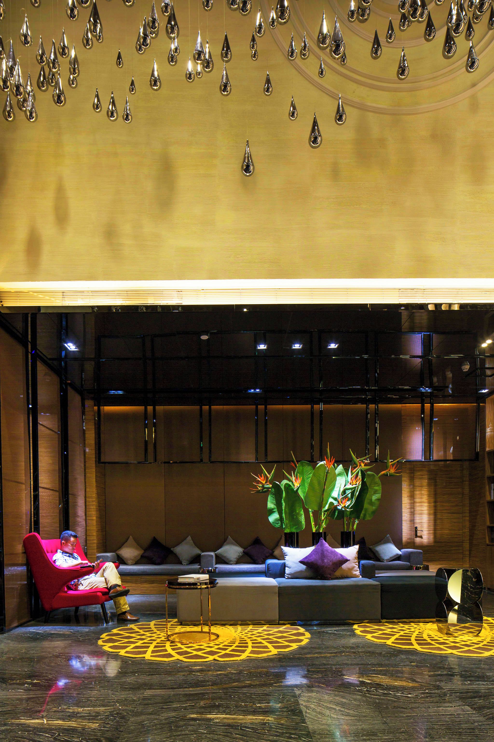 A modern lobby with a seating area, a reception desk, and a decorative ceiling.