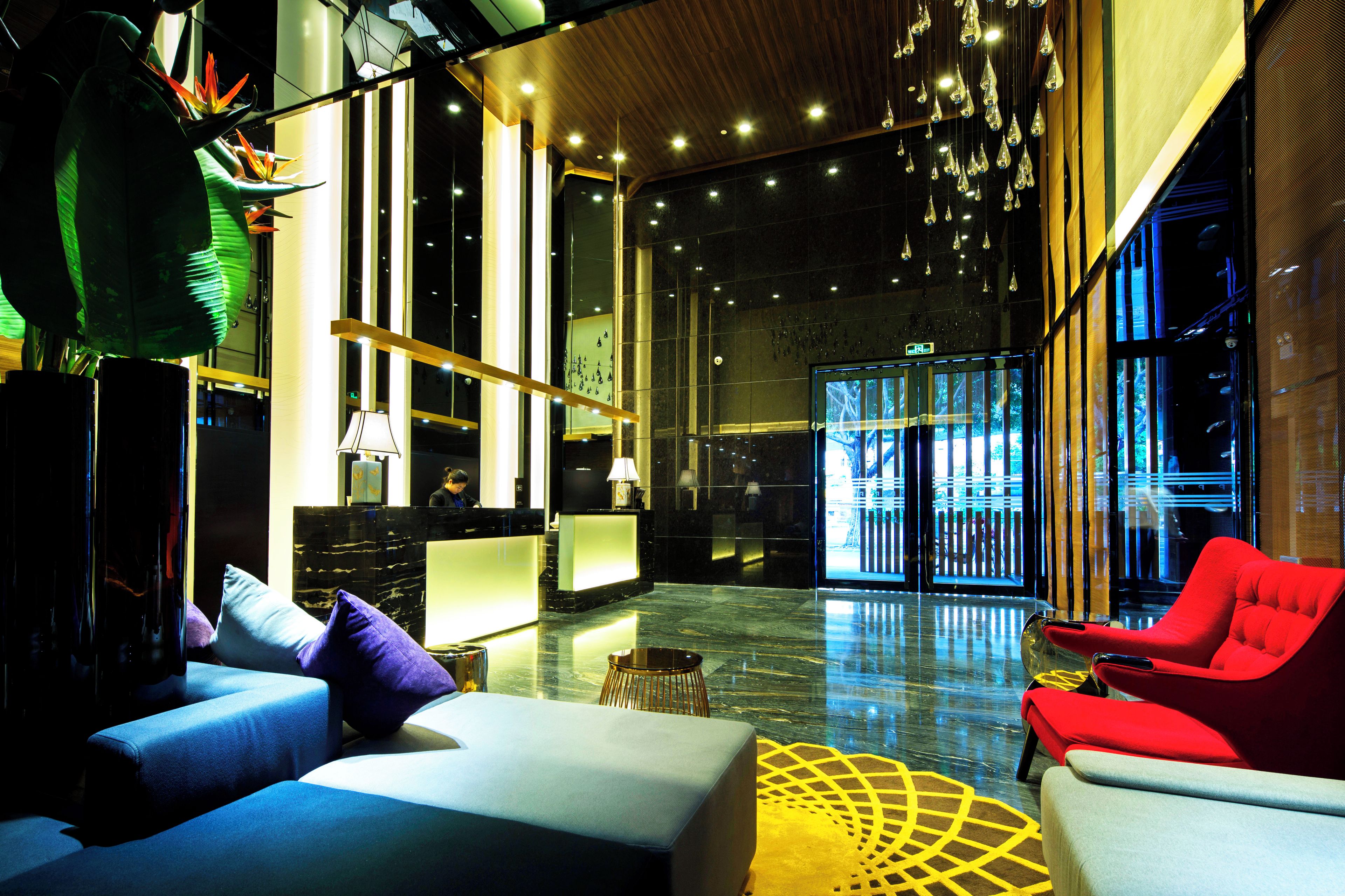 Eine moderne Lobby mit einer Rezeption, einer Sitzecke und großen Fenstern.