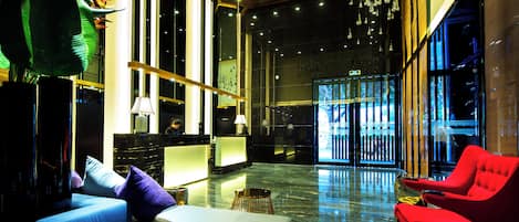 A modern lobby with a reception desk, seating area, and large windows.