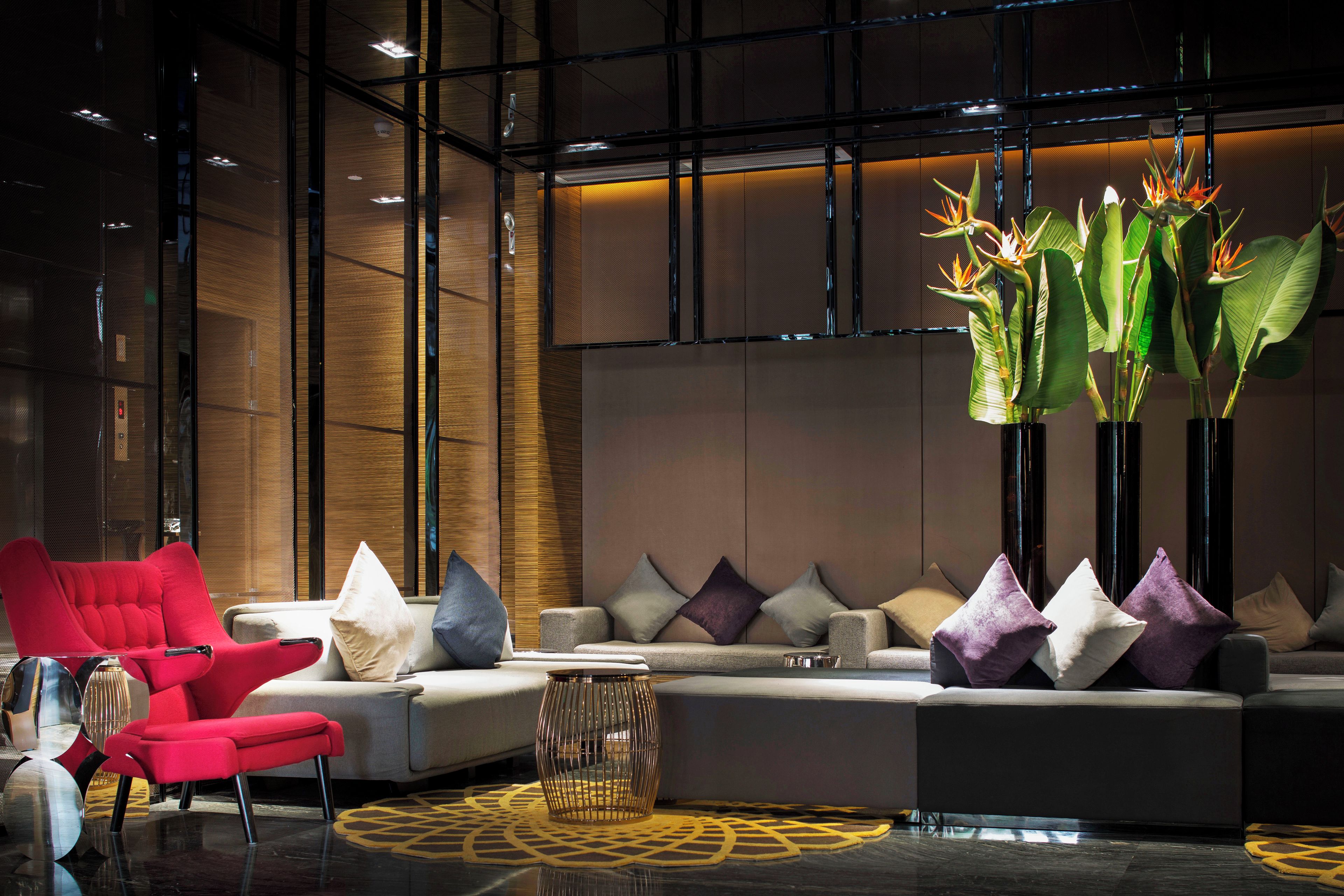 A modern interior with a sectional sofa, red armchairs, and decorative plants.