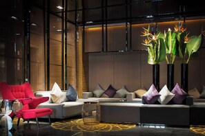 Um interior moderno com sofá seccional, poltronas vermelhas e plantas decorativas.