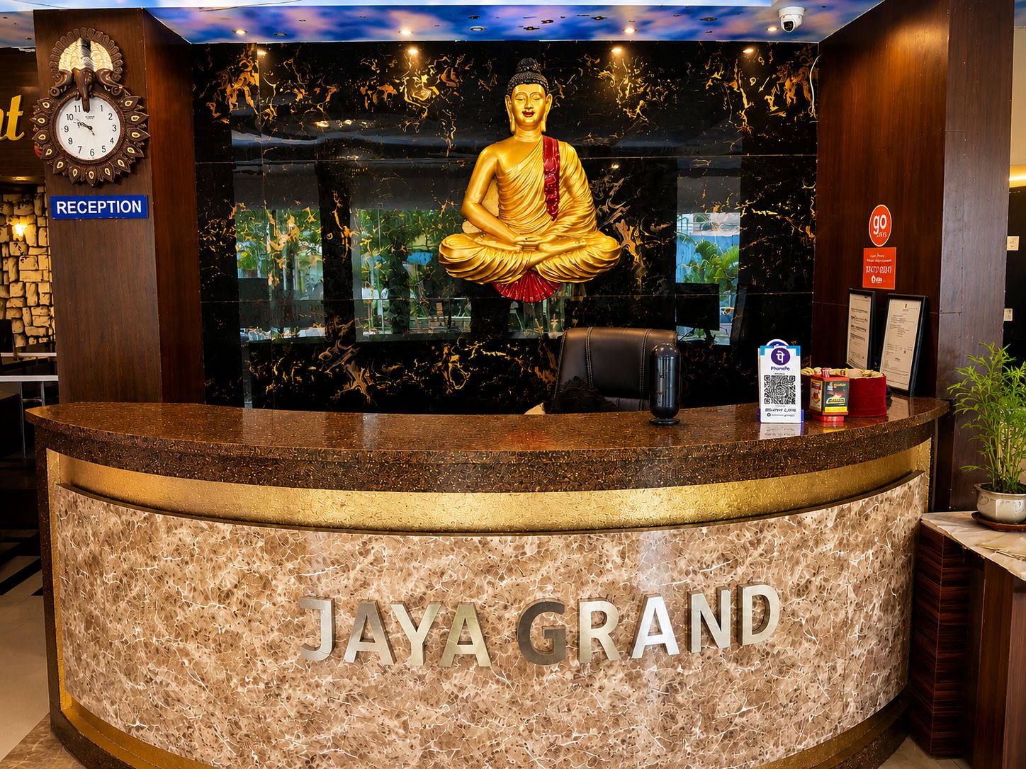 Una recepción con una estatua de Buda, un reloj y un letrero que dice 'JAYA GRAND'.