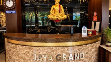 Una recepción con una estatua de Buda, un reloj y un letrero que dice 'JAYA GRAND'.