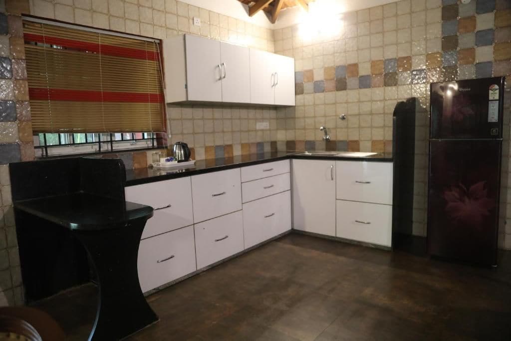 A kitchen with white cabinets, a black countertop, a sink, and a refrigerator.
