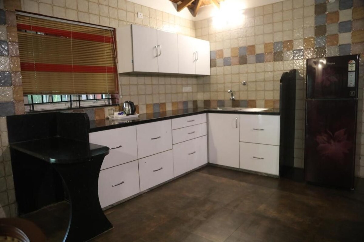 A kitchen with white cabinets, a black countertop, a sink, and a refrigerator.
