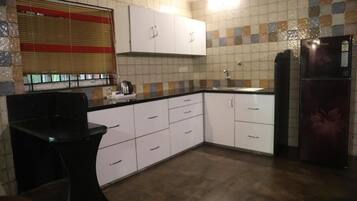 A kitchen with white cabinets, a black countertop, a sink, and a refrigerator.