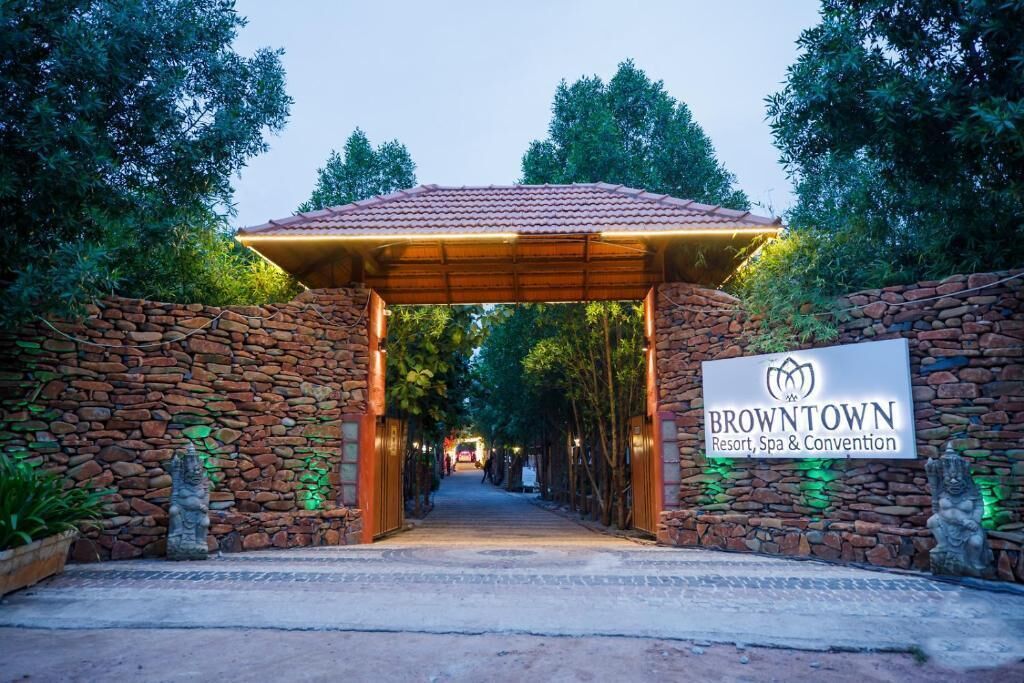 A stone archway leading to a covered entrance with a sign for BrownTown Resort, Spa & Convention.