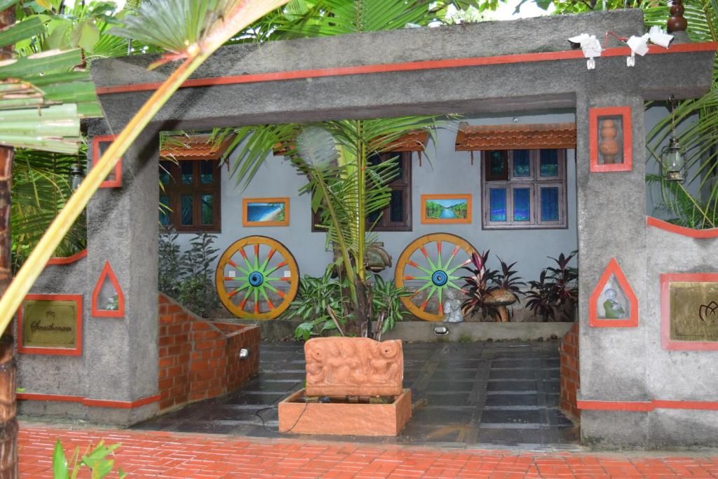 A stone entrance with a staircase leading up, surrounded by tropical plants and framed pictures.