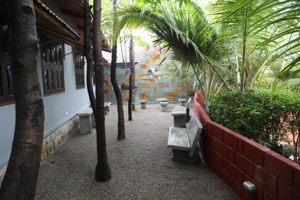 Un patio al aire libre con bancos, un muro de ladrillo rojo y una palmera.