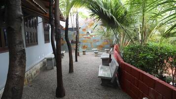 Un patio al aire libre con bancos, un muro de ladrillo rojo y una palmera.