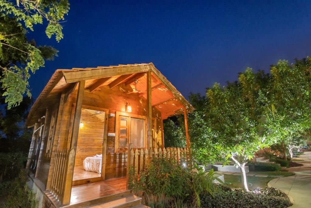 Eine Holzhütte mit Veranda, einem Bett und einem kleinen Garten.