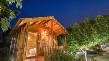 Eine Holzhütte mit Veranda, einem Bett und einem kleinen Garten.