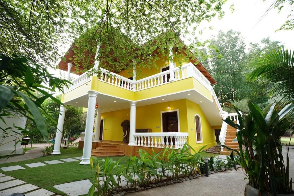 Un edificio de dos pisos con fachada amarilla, balcones blancos y una escalera que lleva al nivel superior.