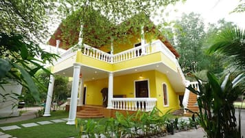 Un edificio de dos pisos con fachada amarilla, balcones blancos y una escalera que lleva al nivel superior.