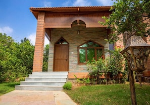 A two-story house with a brick facade, a wooden door, and a window with a wooden frame.