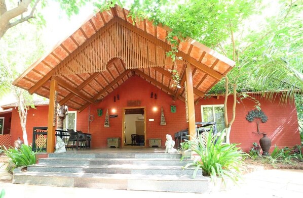 A building with a red facade, a wooden porch, and steps leading to the entrance.