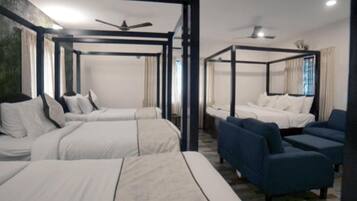 Ein Hotelzimmer mit einem Himmelbett, einer Sitzecke und einem Deckenventilator.