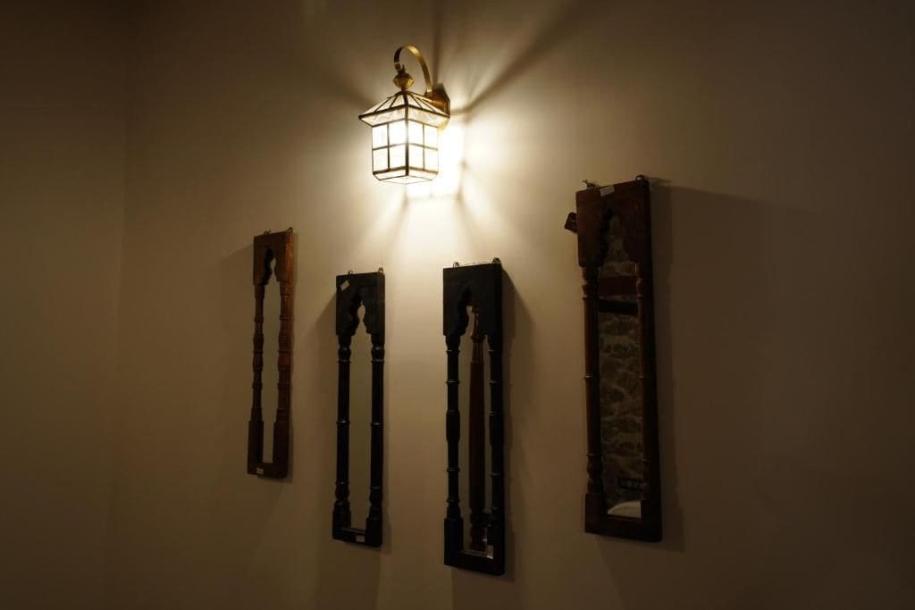 A wall with a hanging light fixture and three vertical wooden structures.