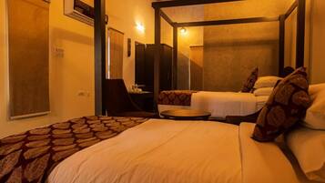 A hotel room with a four-poster bed, a desk with a chair, and a small round table.