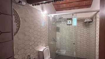 A bathroom with a hexagonal tile pattern, a sink with a basin, a shower area, and a door with a handle.